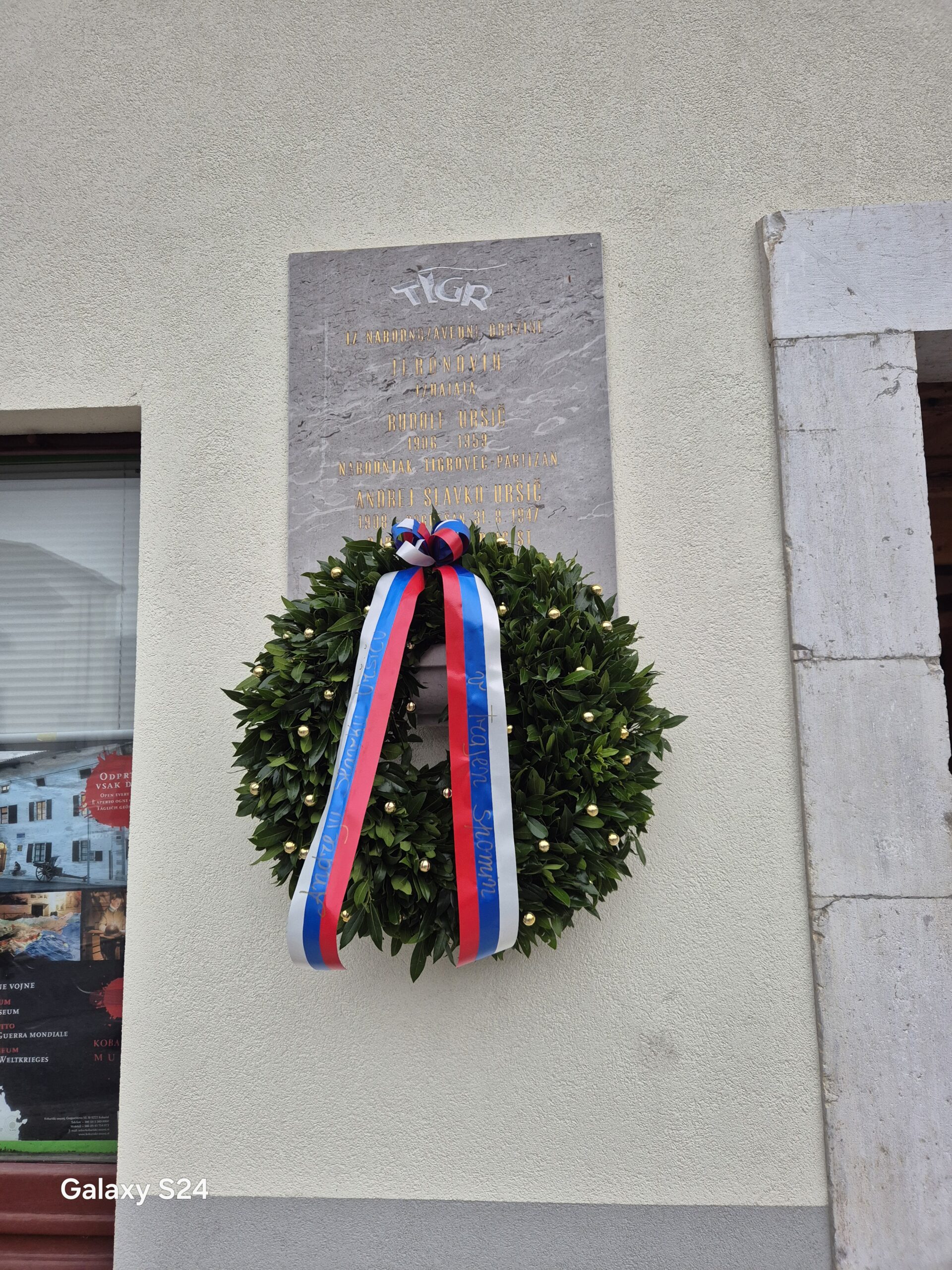 Venec in spominska plošča na pročelju Jeronove domačije v Kobaridu.